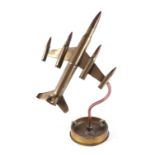 A trench art jet plane, constructed from brass artillery rounds and bullets, mounted on a 1944 dated