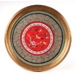 A Chinese embroidered silk work panel, depicting a bird with flowers, 28cm diameter, framed and