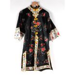 A Chinese silk embroidered robe decorated with scrolling flowers, on a black ground.