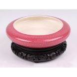 A Chinese pink glazed crackle ware brush washer, with a hard wood stand, 16cm diameter.