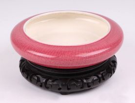 A Chinese pink glazed crackle ware brush washer, with a hard wood stand, 16cm diameter.