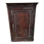 A George III oak hanging corner cabinet, having a panelled door enclosing shelves, 83cm wide.