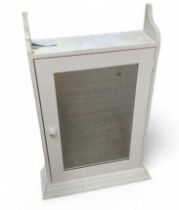 A white painted wall cupboard, with mirror set int