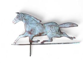 A weathered copper figure of a running horse, with