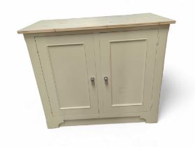 A cream cupboard with an unfinished pine top, the