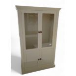 A cream cupboard, the top with two glazed doors, o