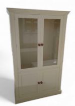 A cream cupboard, the top with two glazed doors, o