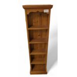 A slim pine bookcase, with five fixed shelves, and