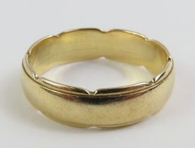 A 9ct gold wedding ring with a scalloped edge, by