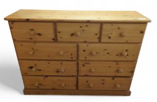 A modern pine chest of three short drawers over th