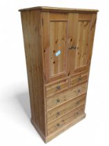 A modern pine cupboard with pair of doors above tw