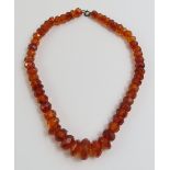 A row of graduated, facetted amber beads, with bas