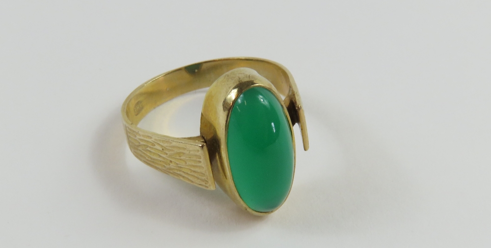 A ring set with an elongated oval cabochon cut gre