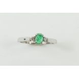 An emerald and diamond three stone ring, the oval