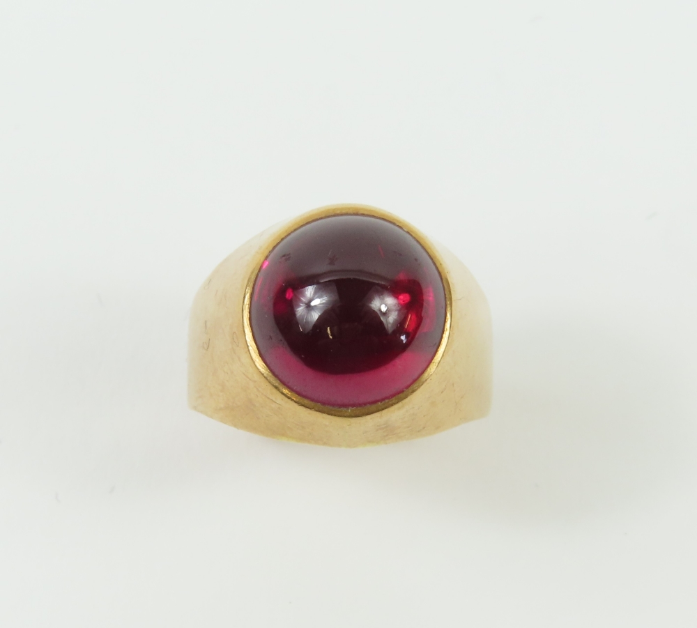 A signet ring set with a round synthetic ruby cabochon