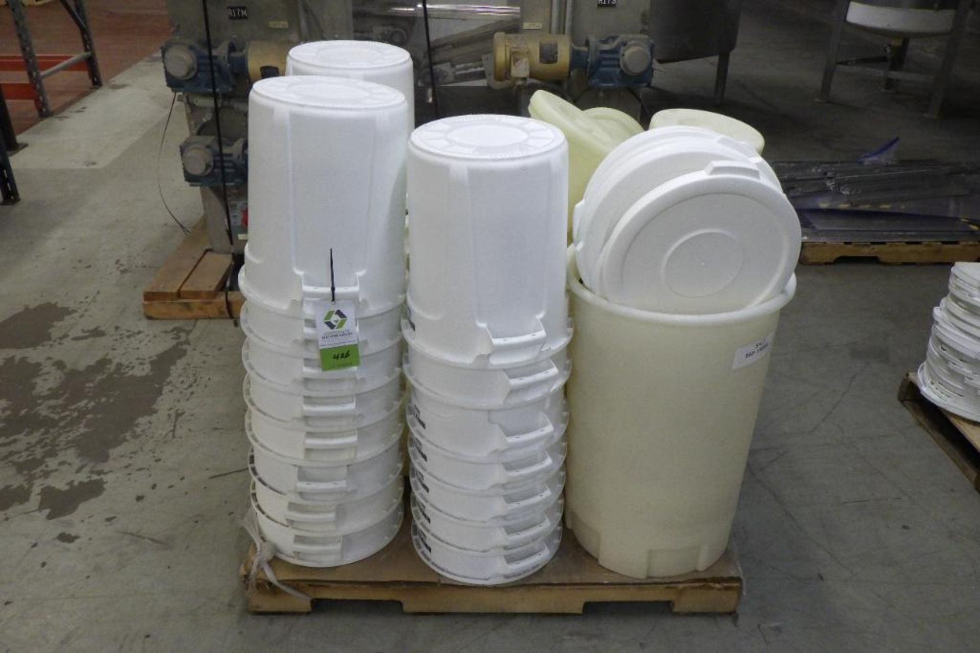 Pallet of white Rubbermaid trash bins with lids