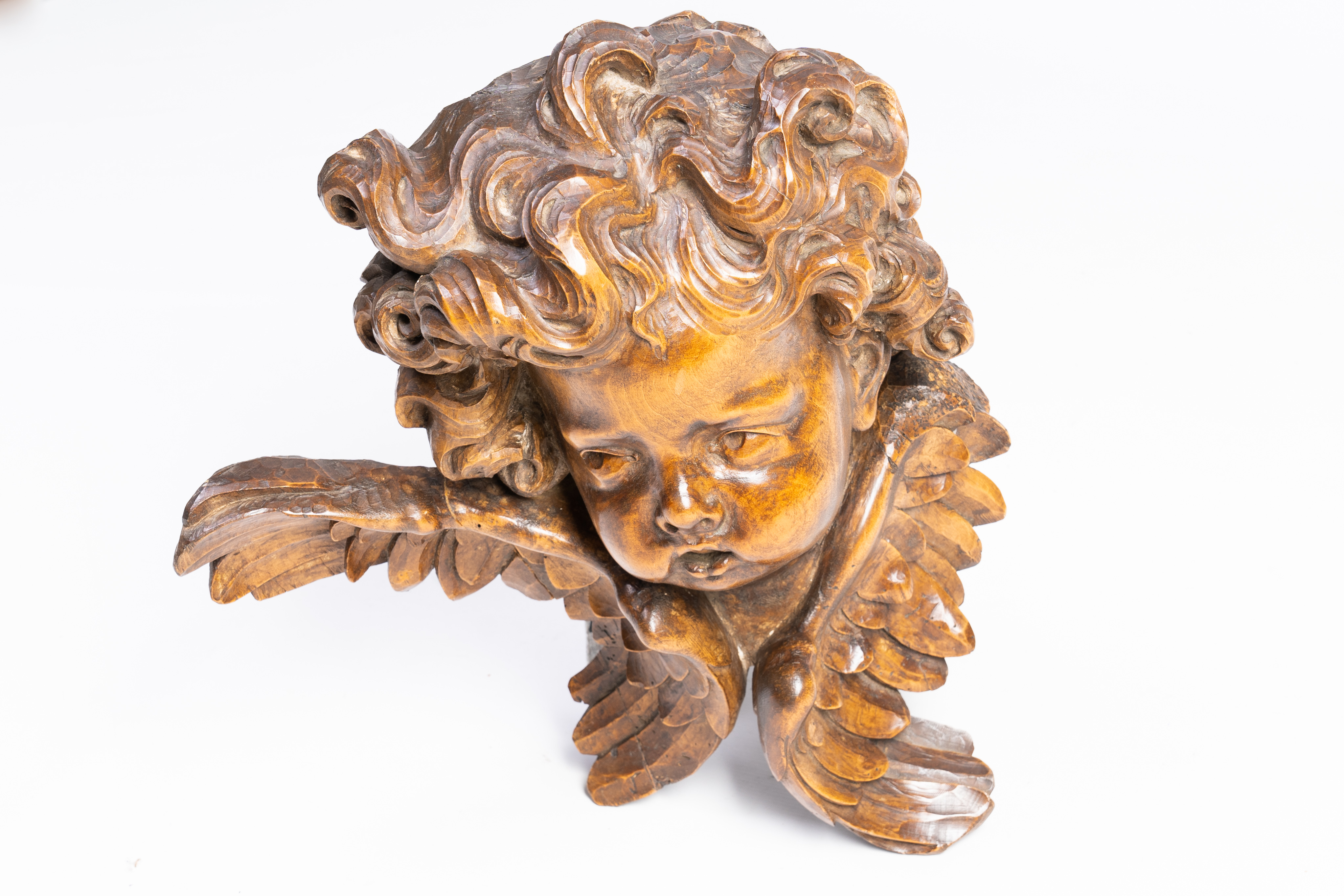 A large carved wood Baroque style head of a mischievous angel, 19th C.