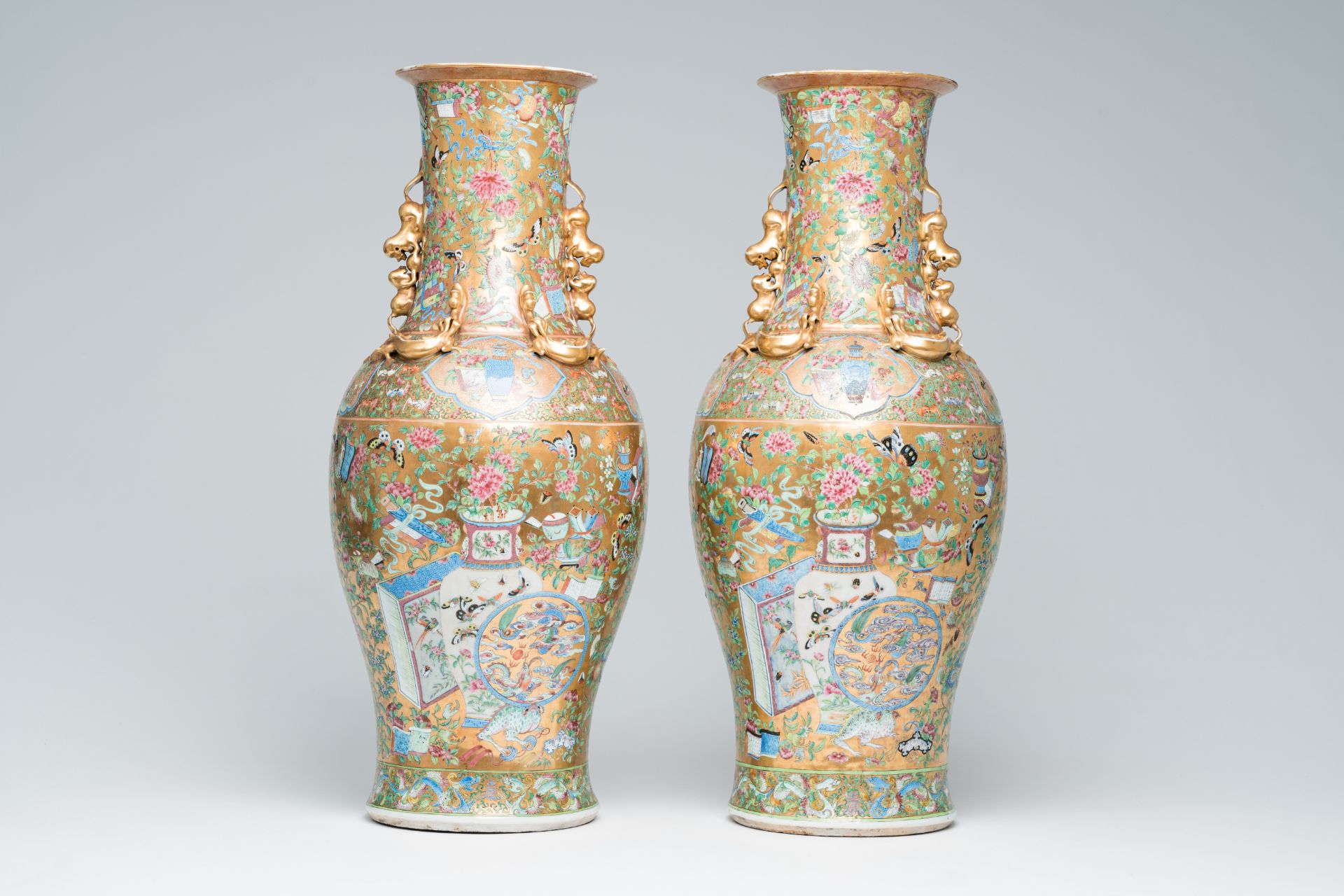 A pair of Chinese Canton famille rose gold ground vases with birds and butterflies among blossoming