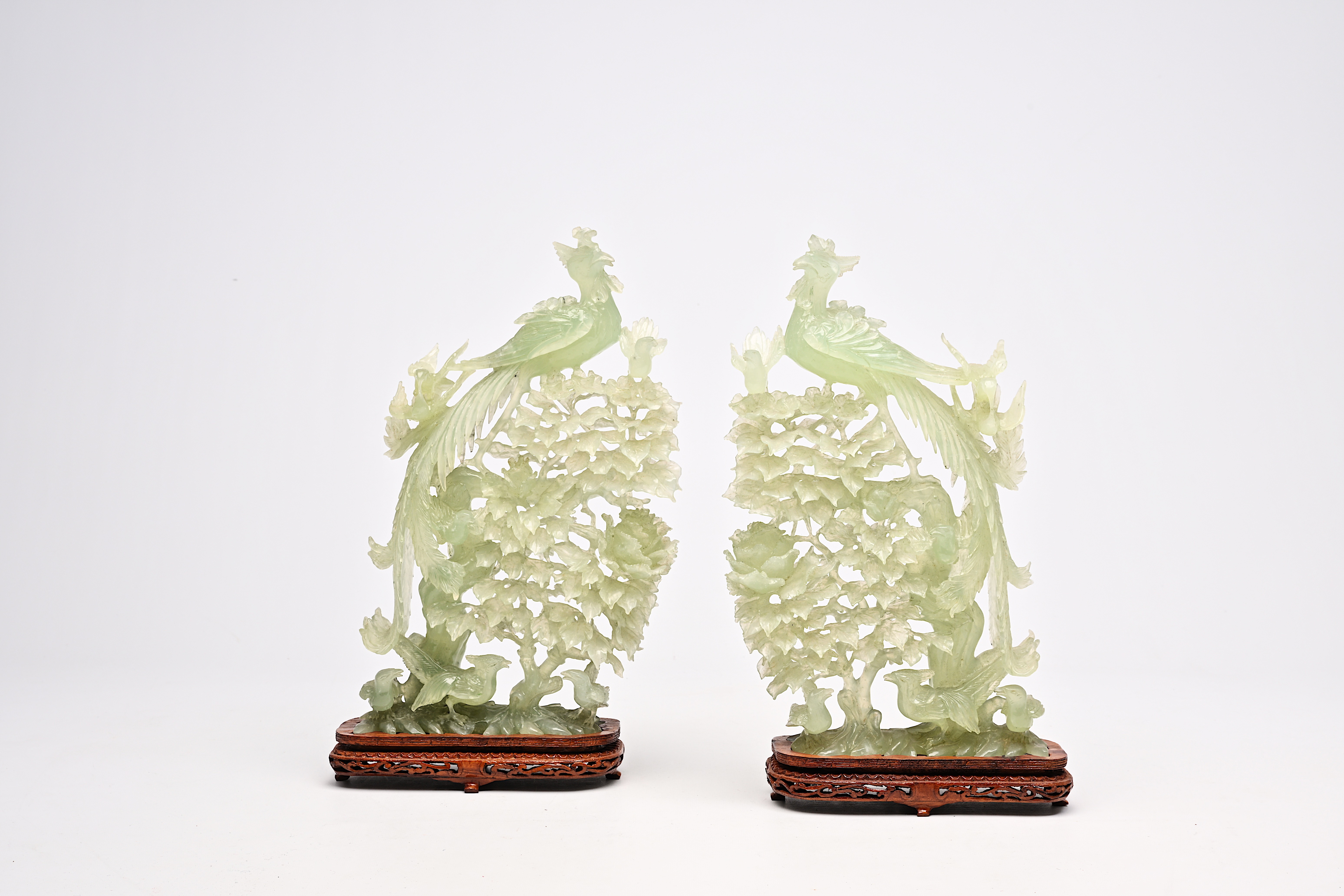 A pair of large Chinese carved jadeite groups with a phoenix among blossoming branches, 20th C.