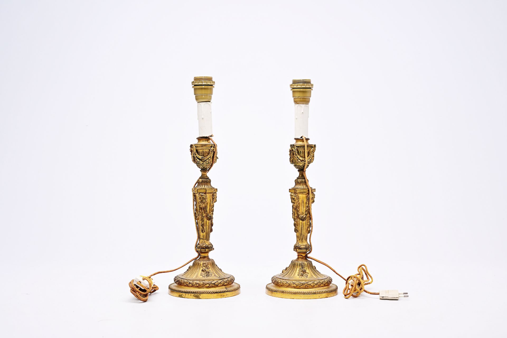 A pair of French Neoclassical gilt bronze candlesticks with lion heads and garlands mounted as lamps