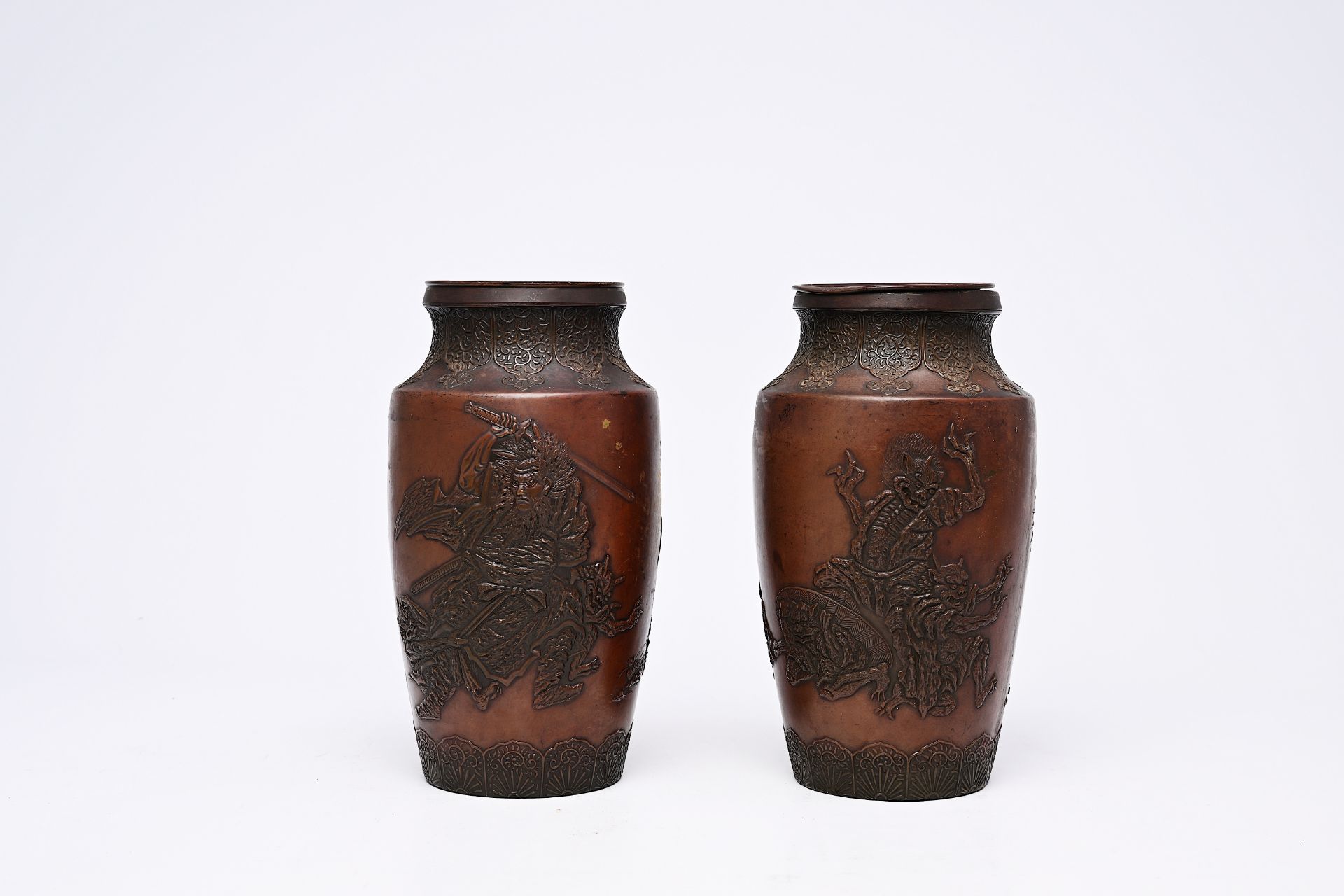 A pair of Japanese bronze vases with relief design of demons in a landscape, Meiji, 19th/20th C.