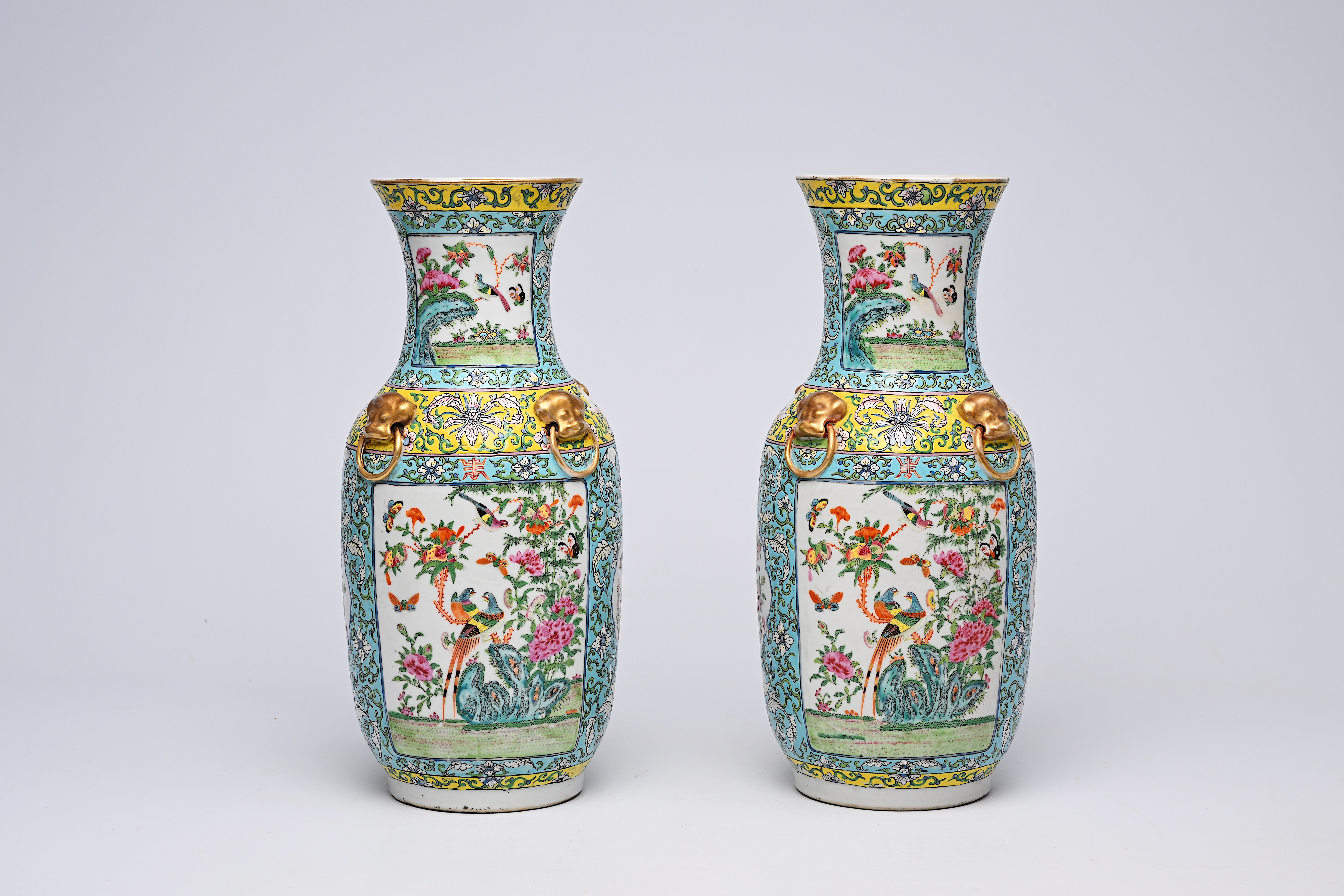 A pair of Chinese Canton famille rose turquoise ground vases with birds and butterflies among blosso