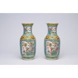 A pair of Chinese Canton famille rose turquoise ground vases with birds and butterflies among blosso