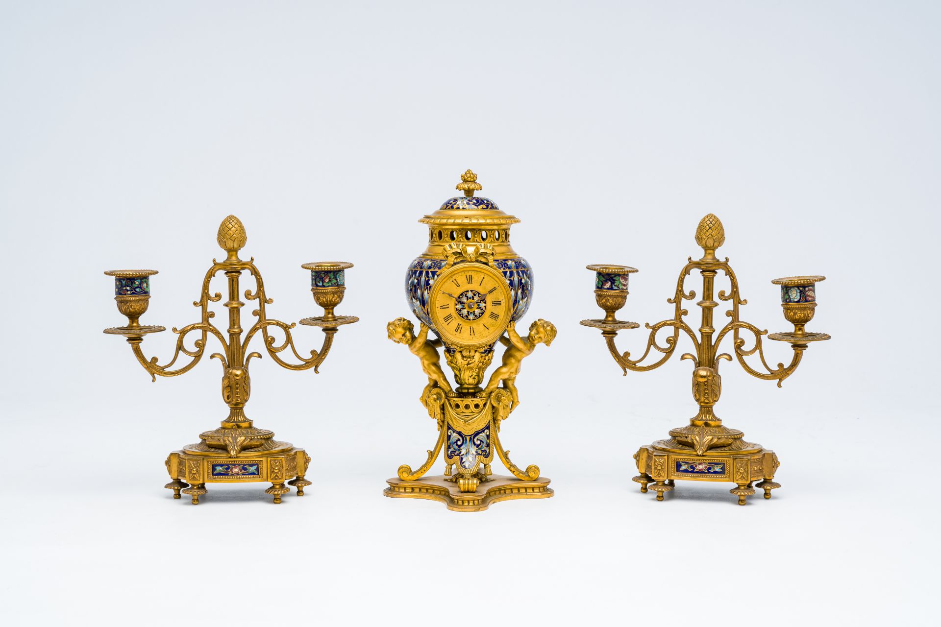 A French gilt bronze and cloisonne three-piece clock garniture with putti, 19th C.