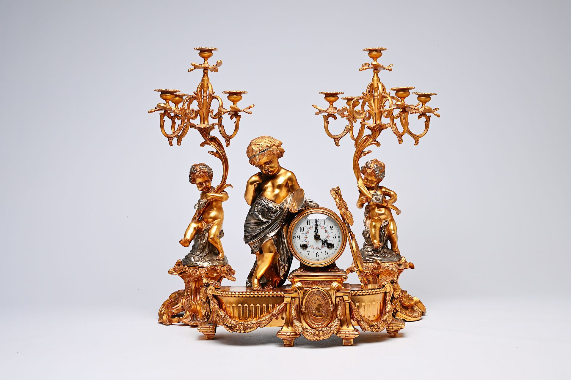 A French three-piece partly gilt metal clock garniture with putti, 20th C. - Image 2 of 11