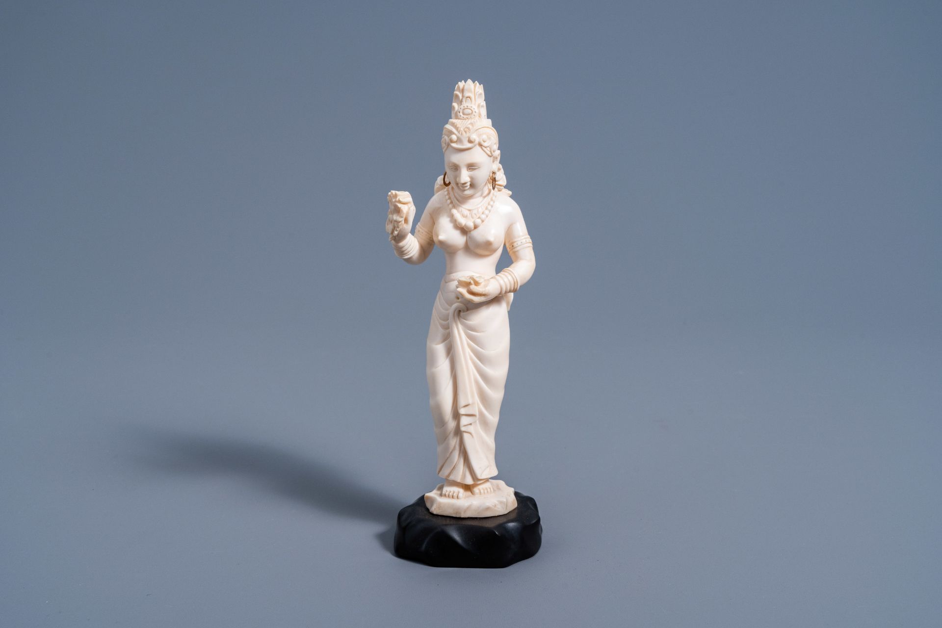 An Indian carved ivory figure of a goddess holding flowers in her hands, ca. 1900