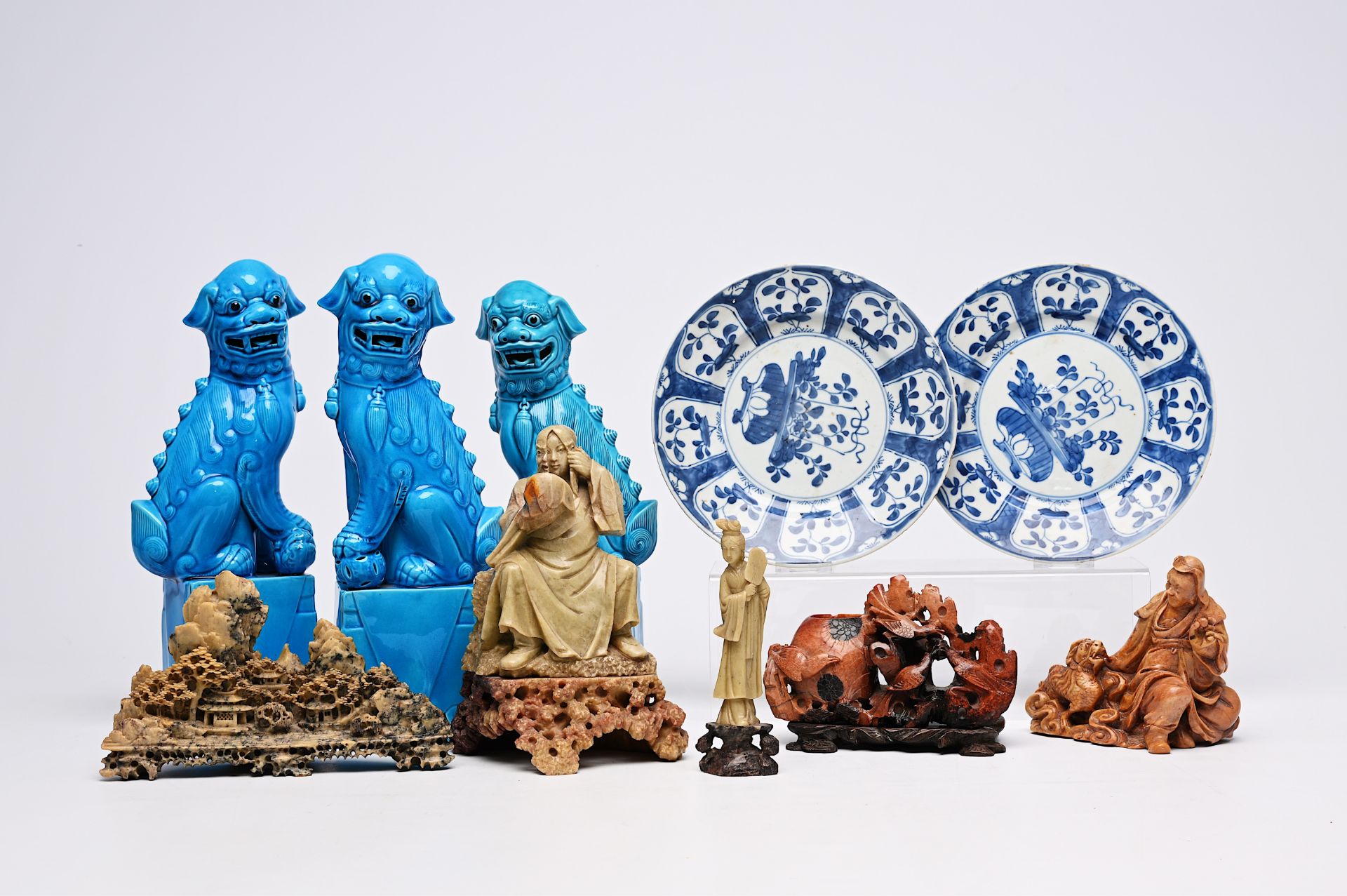 Five Chinese soapstone sculptures, three turquoise glazed lions and a pair of blue and white plates,