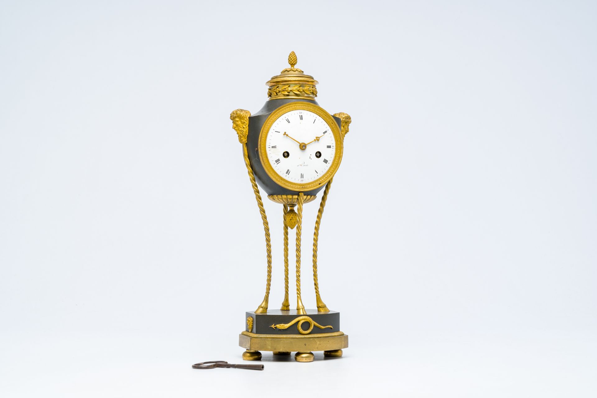 An elegant French Neoclassical patinated and gilt bronze mantel clock with mascarons, 19th C.
