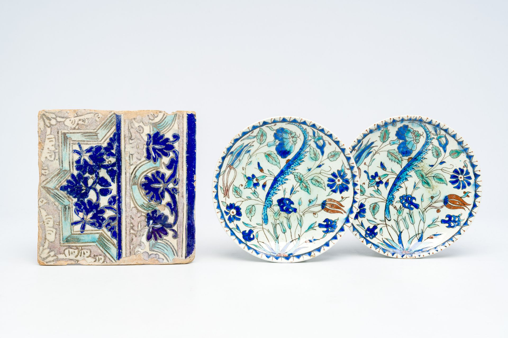 A pair of polychrome Kutahya Isnik style plates and an Iranian tile, 19th C.