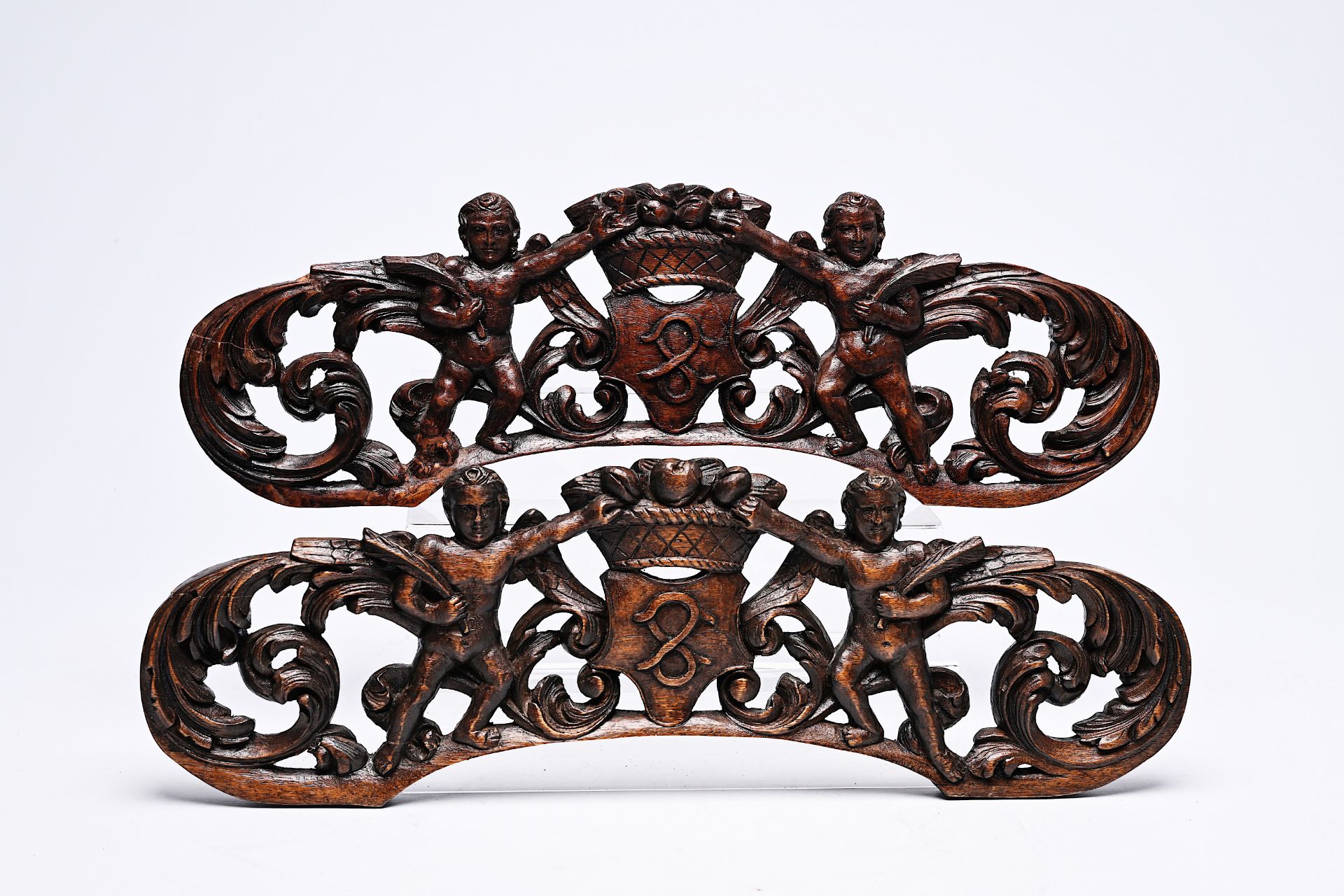 A pair of crowned reticulated wood fragments with putti,