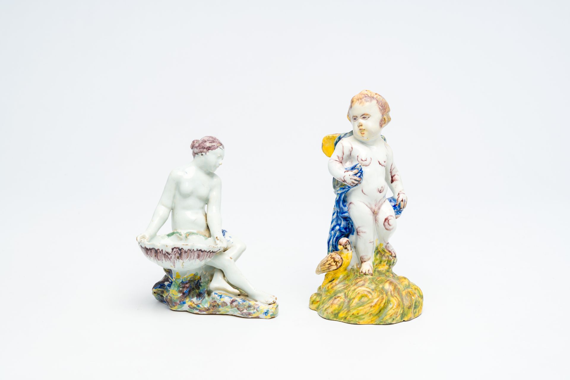 A polychrome 'putto and bird' faience sculpture and a 'lady with a shell' salt cellar, Delft or Brus
