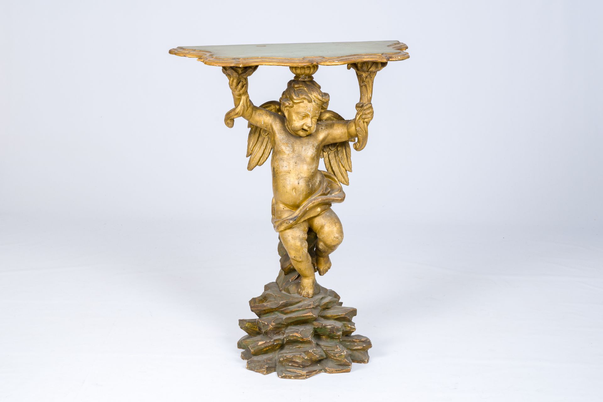 A gilt and polychrome decorated wood wall console in the shape of an angel standing on a rock, 18th
