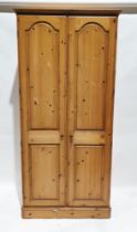 20th century pine two-door wardrobe opening to reveal an adjustable shelf and clothes rail, one door