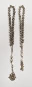 Two strings of continental silver-coloured metal worry beads, pierced basket-pattern with tassel