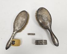 Two silver-mounted dressing table brushes, one with monogrammed initials, a white metal hinged