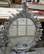 20th century silver painted bevelled edged wall mirror of oval form, ornately decorated with