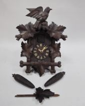 Carved Black Forest wood striking cuckoo clock, early 20th century, surmounted with a bird on
