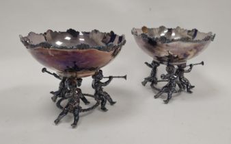 Pair silver-plated pedestal bowls, each with scroll and shell border, on three putto supports,