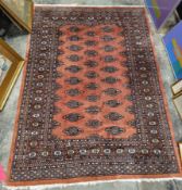 Eastern wool rug with madder field, having two rows of lozenges alternating with hooked motifs and
