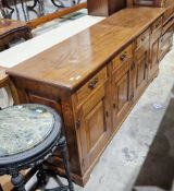 Reproduction oak low dresser by Kevin Burks, having four short drawers above cupboards enclosed by