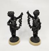 After Moreau, pair of bronze figures of cherubs, the standing boy and girl each holding a garland of