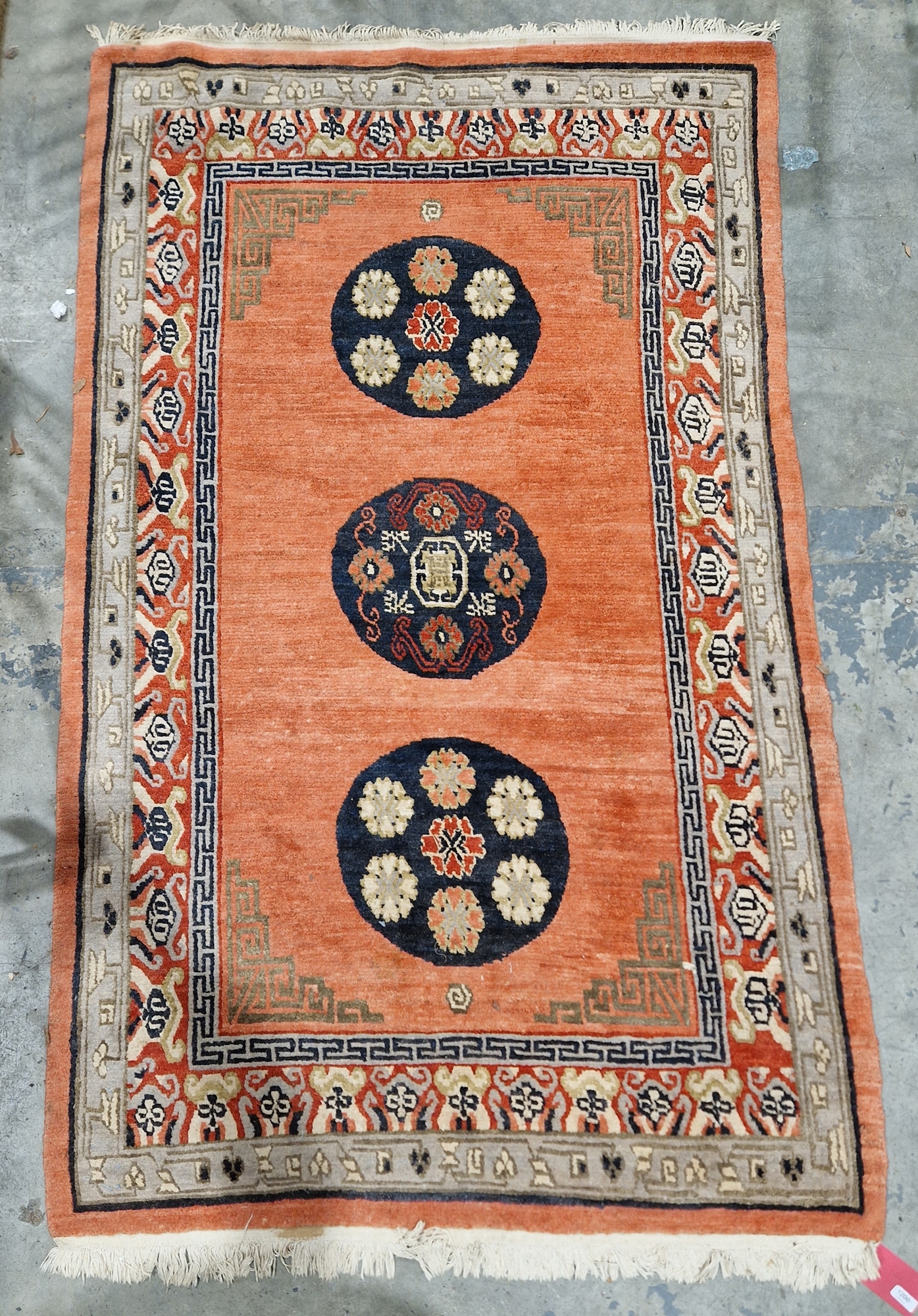 Oriental-style red ground rug, the central panel with three circular floral medallions and