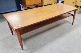 Mid-century teak coffee table of rectangular form with a newspaper tray, on turned legs, 41cm high x