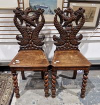 Pair of Victorian carved oak hall chairs having twin dolphin and eagle backs, panel seats on