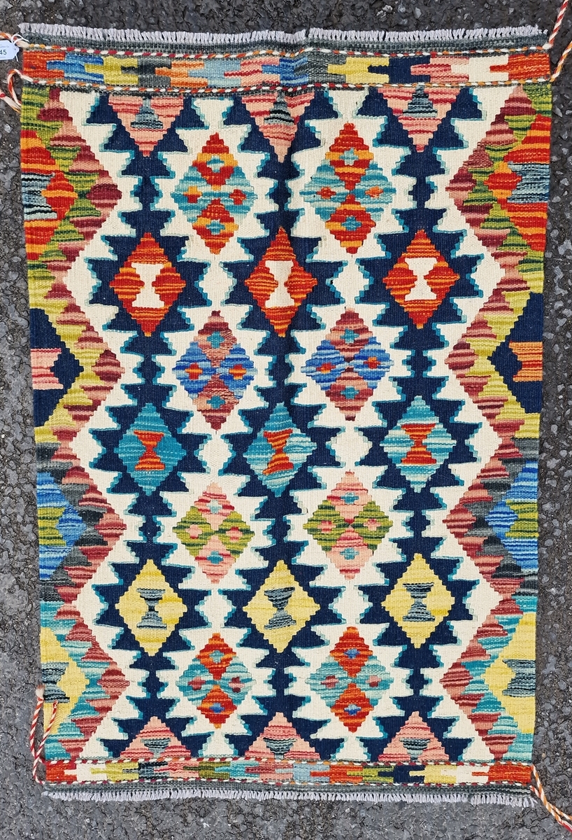 Chobi kilim, woven with a geometric medallion in red, blue and ochre reserved on a cream ground