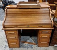 Early 20th century oak roll-top desk, the top with tambour cover and fitted interior, over one